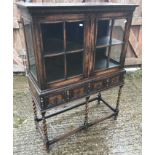 An early 20th Century oak display cabinet in the 17th Century style, the two glazed and barred doors
