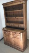 A pine dresser in the Victorian manner, the top with three plate racks above four small drawers on a