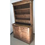 A pine dresser in the Victorian manner, the top with three plate racks above four small drawers on a