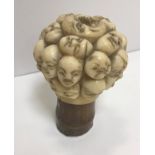 A 19th Century Japanese carved ivory cane handle set as multiple faces / masks, the ivory finial