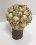 A 19th Century Japanese carved ivory cane handle set as multiple faces / masks, the ivory finial