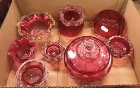 A collection of Cranberry glass to include lidded bowl, two lidded jars, two jugs, a basket etc