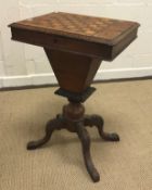 A Victorian walnut and parquetry inlaid games top sewing table on turned column support to carved