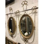 A pair of circa 1900 gilt and gesso framed oval wall mirrors with fine harebell drape and ribbon