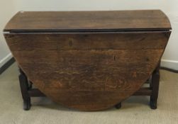 An 18th Century oak oval gate-leg drop-leaf dining table on turned and block supports to splayed