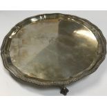 A mid 20th Century silver salver with engraved initials and raised on three claw and ball feet