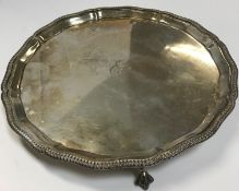 A mid 20th Century silver salver with engraved initials and raised on three claw and ball feet