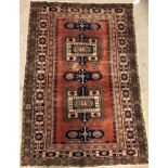 A Persian carpet, the central panel set with repeating geometric motifs on a red ground,