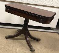 A Regency mahogany and rosewood inlaid fold-over tea table on turned and ringed centre pedestal to