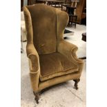 A late Victorian upholstered wing back scroll arm chair on cabriole front legs to pad feet,