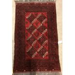A Bokhara rug, the central panel set with two rows of repeating medallions on a red ground,