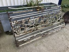 A pair of painted wrought iron garden fence sections with scrolling decoration,