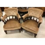 A pair of Victorian carved mahogany framed salon tub chairs with buttoned back over turned rail