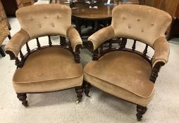 A pair of Victorian carved mahogany framed salon tub chairs with buttoned back over turned rail