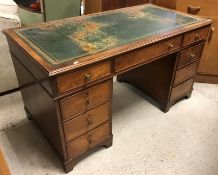 A mahogany kneehole desk, the tooled and gilded leather insert top over three frieze drawers,