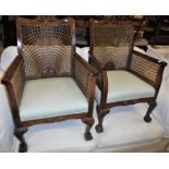 A pair of early to mid 20th Century mahogany framed and caned Bergere armchairs with upholstered
