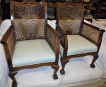 A pair of early to mid 20th Century mahogany framed and caned Bergere armchairs with upholstered