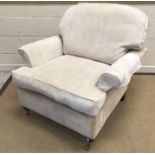 A modern upholstered scroll arm chair on turned front legs to brass caps and castors,