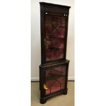 A modern reproduction mahogany corner cabinet with blind fretwork carved frieze over two astragal