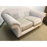 A modern fawn upholstered two seat sofa in the Victorian manner with scroll arms on turned legs to