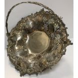 A Victorian pierced and embossed silver fruit basket with swing handle raised on a pedestal base,