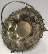 A Victorian pierced and embossed silver fruit basket with swing handle raised on a pedestal base,