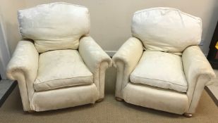 A pair of modern cream upholstered scroll arm chairs on squat bun feet,