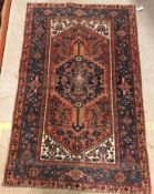 A Persian rug, the central panel set with lozenge shaped medallion on a red, blue and cream ground,