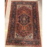 A Persian rug, the central panel set with lozenge shaped medallion on a red, blue and cream ground,