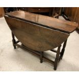 A 19th Century oak oval gate-leg drop-leaf dining table on turned and ringed supports to block feet