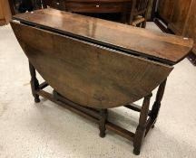 A 19th Century oak oval gate-leg drop-leaf dining table on turned and ringed supports to block feet