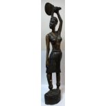 A carved king ebony full standing figure of a woman with paddle above her head,