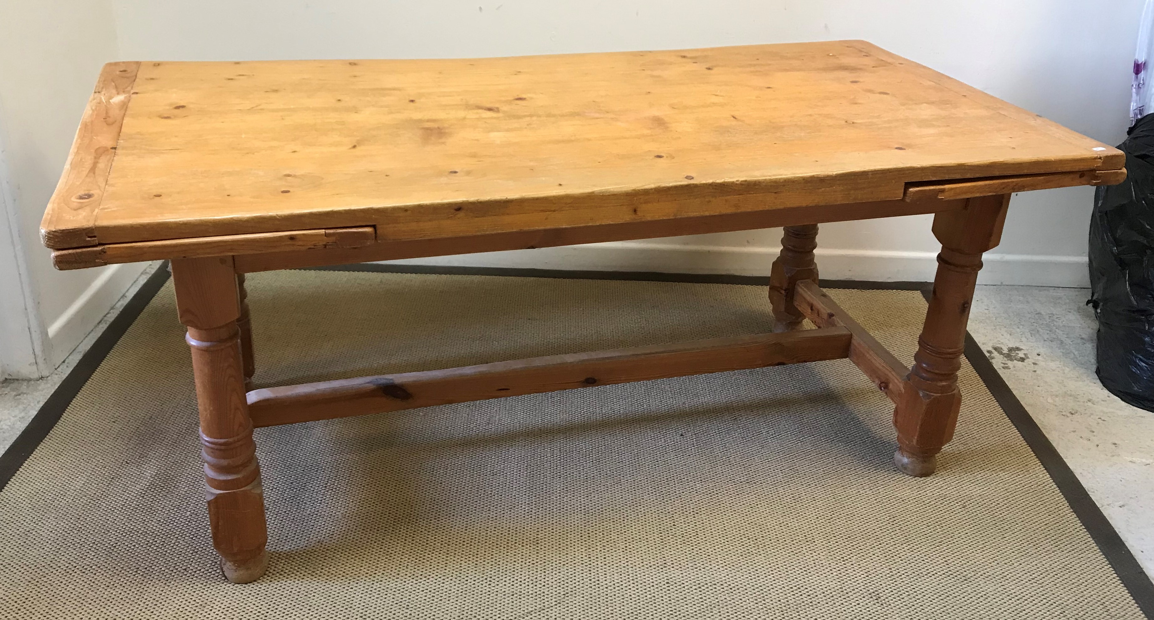 A modern pine farmhouse style draw leaf kitchen table on turned and ringed supports united by a
