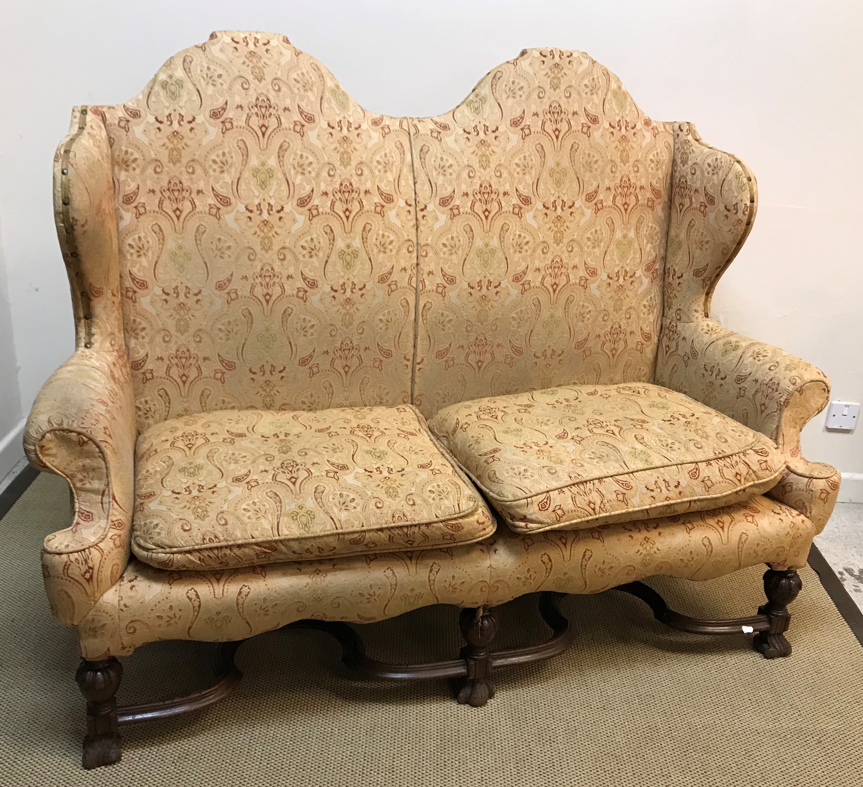 A circa 1900 upholstered wing back scroll arm two seat sofa in the 17th Century style,