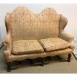 A circa 1900 upholstered wing back scroll arm two seat sofa in the 17th Century style,