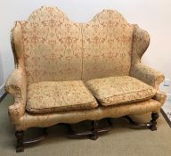 A circa 1900 upholstered wing back scroll arm two seat sofa in the 17th Century style,