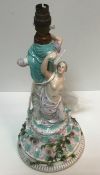 A Joseph Gaspard Robert porcelain table centre as two figures on a rose decorated socle base