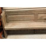 A circa 1900 stained pine pew of plain form on plank end supports,