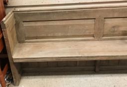 A circa 1900 stained pine pew of plain form on plank end supports,