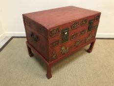 A Chinese red lacquered coffer on associated stand, the front with gilt medallion decoration,