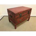 A Chinese red lacquered coffer on associated stand, the front with gilt medallion decoration,