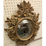 A Florentine carved giltwood and gesso oval framed wall mirror with floral and foliate decoration,