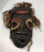 An African tribal mask with painted and carved decoration with grass hair 35 cm high