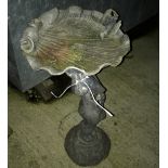 A 20th Century lead bird bath as a putto holding aloft a shell,