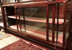 An early 20th Century mahogany framed and glazed shop display counter with rear sliding doors