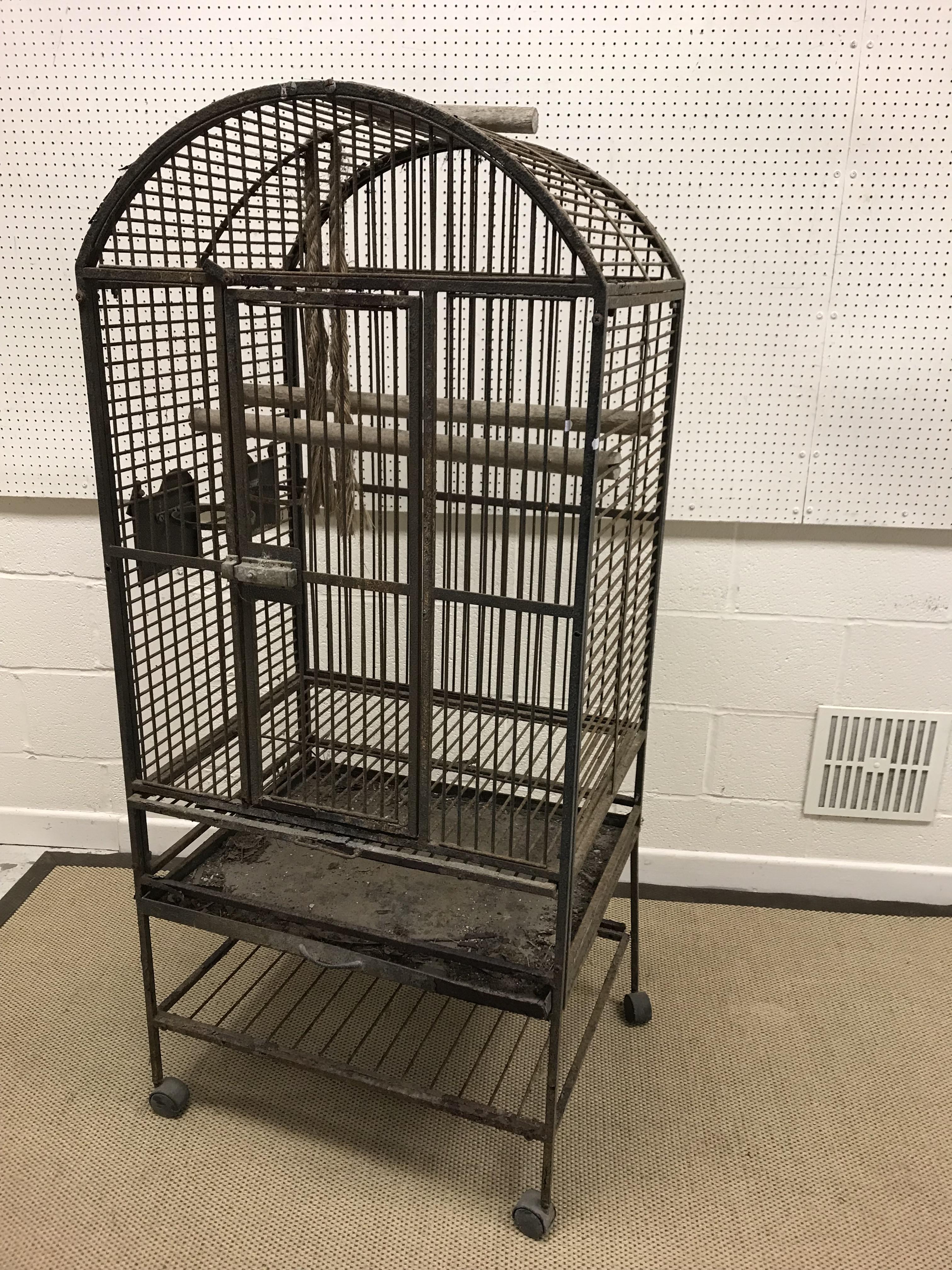 A vintage wrought iron parrot cage with wooden rails and bowl holders, 70.5 cm x 56.