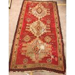 A Kelim rug, the central panel set with three repeating medallions on a red ground,