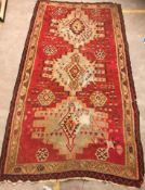 A Kelim rug, the central panel set with three repeating medallions on a red ground,