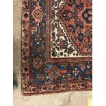 A Persian rug, the central panel set with lozenge shaped medallion on a red, blue and cream ground,