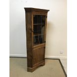 A modern oak free-standing corner cupboard with leaded glazed door enclosing two shelves over a